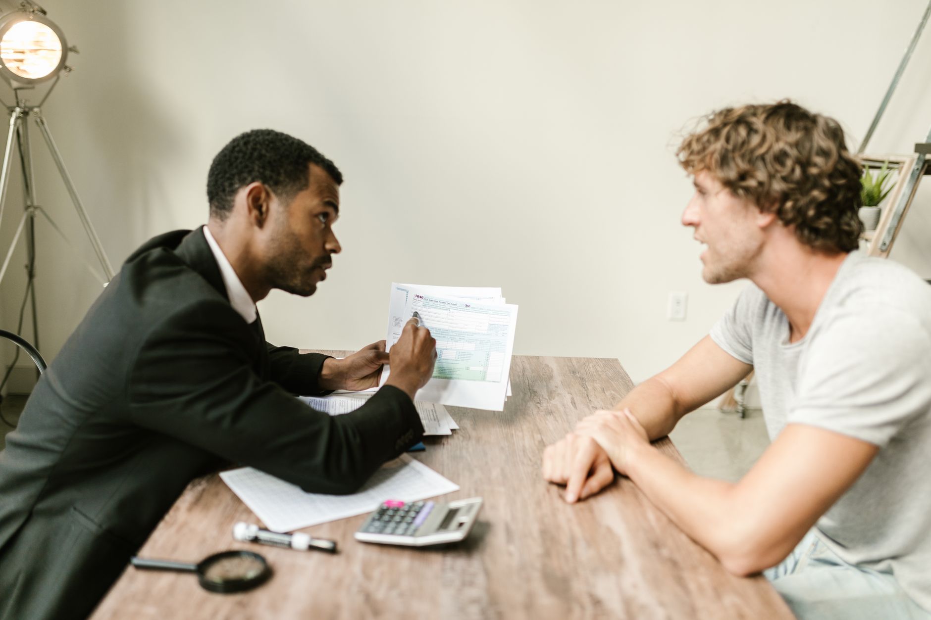 Consultor a explicar a papelada a um cliente, numa secretária